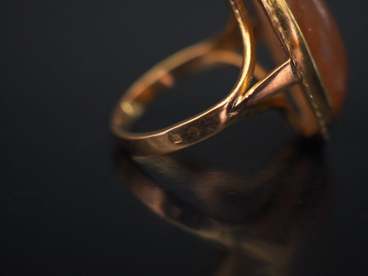 Bague en or jaune de forme ovale, sertie en son centre d'une pierre du