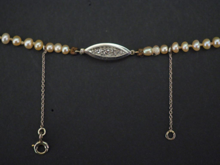 Collier de perles blanches disposées en chute.  Fermoir en or jaune, s