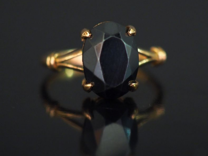 Bague en or jaune, sertie en son centre d’une pierre noire facettée.  
