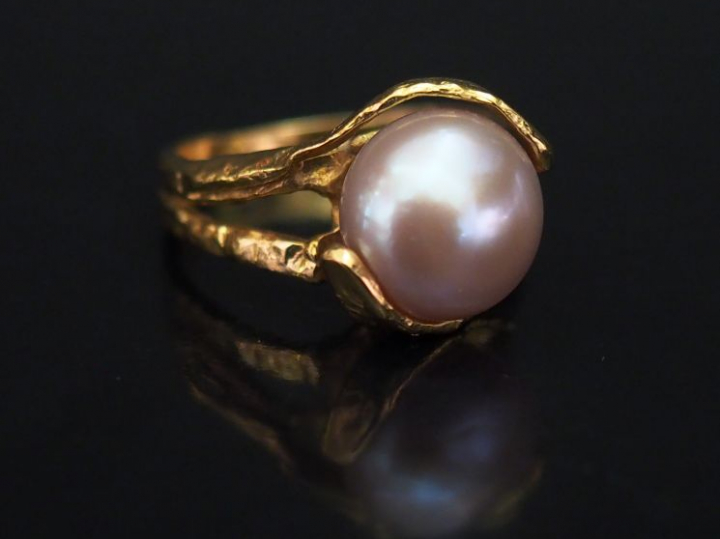 Bague de forme stylisée en or jaune, sertie en son centre d'une perle 