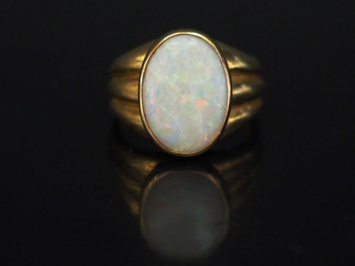 Bague en or jaune, ornée en son centre d’une opale ovale en serti clos