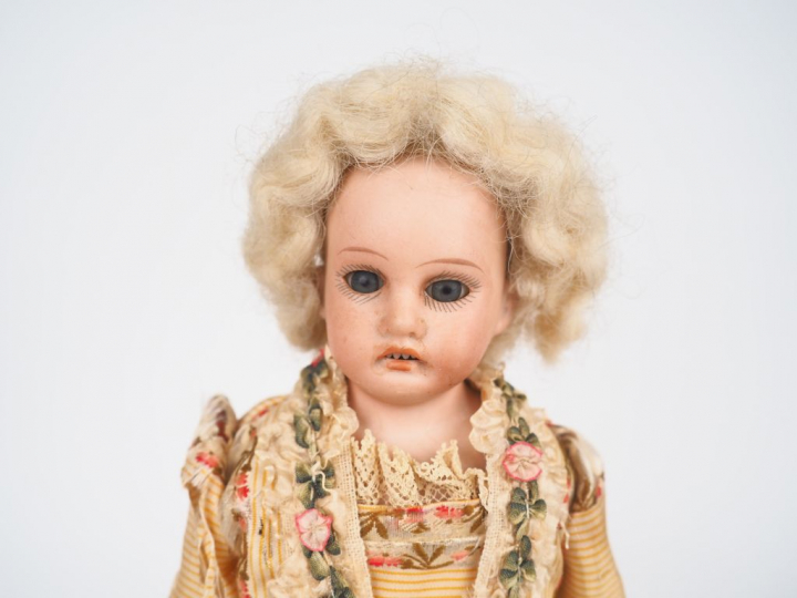 Poupée mécanique, tête porcelaine. H. 29 cm (usures et accidents à la 