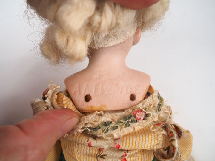 Poupée mécanique, tête porcelaine. H. 29 cm (usures et accidents à la 