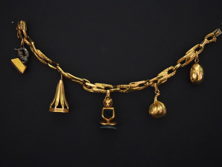Bracelet articulé en or jaune, orné de cinq pendeloques :  - une pende