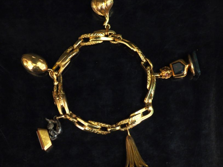 Bracelet articulé en or jaune, orné de cinq pendeloques :  - une pende