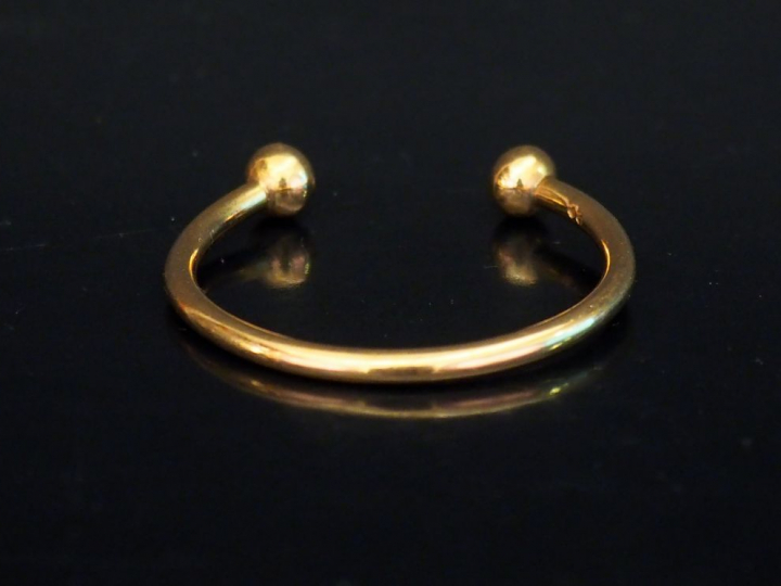 Bracelet jonc d'enfant en or jaune, à décor de boules aux extrêmités. 