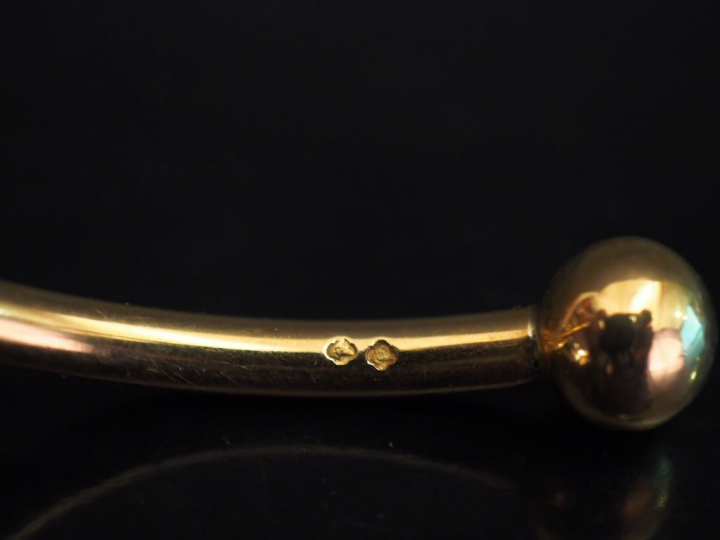 Bracelet jonc d'enfant en or jaune, à décor de boules aux extrêmités. 