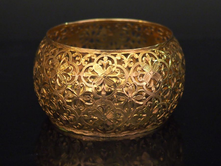 Bracelet manchette de forme bombée en or jaune, à décor ajouré de fleu