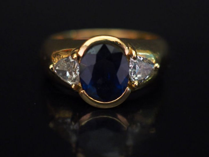 Bague jonc en or jaune, sertie en son centre d'un saphir épaulé de deu