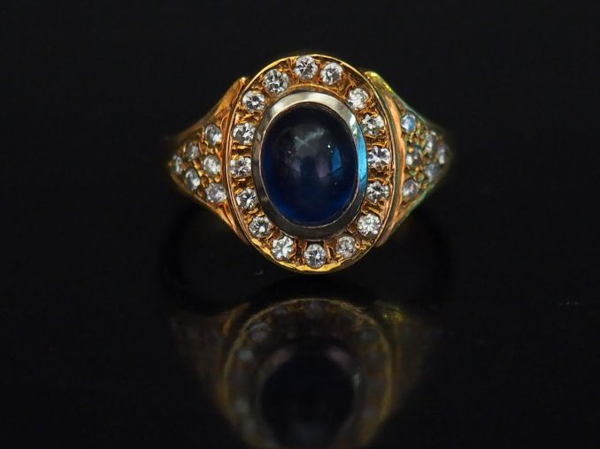 Bague en or jaune, sertie en son centre d'une pierre bleue en cabochon