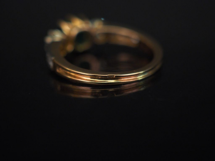 Bague jonc en or jaune, sertie en son centre d'une émeraude épaulée de