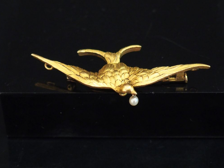 Broche en or jaune, figurant un oiseau aux ailes déployées tenant dans