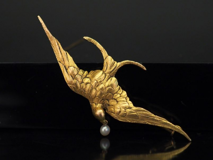 Broche en or jaune, figurant un oiseau aux ailes déployées tenant dans
