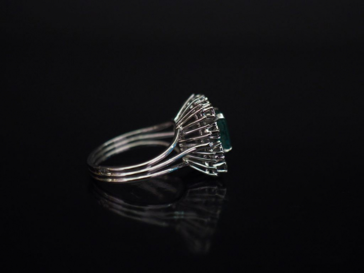 Bague en or blanc, sertie en son centre d'une émeraude entourée de dix