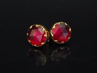 Vente aux enchères Paire de perce-oreilles en or jaune, sertis d'un grenat.  Diam. 0,8 mm