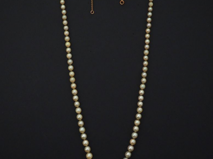 Collier de perles blanches disposées en chute.  Fermoir de forme cylin