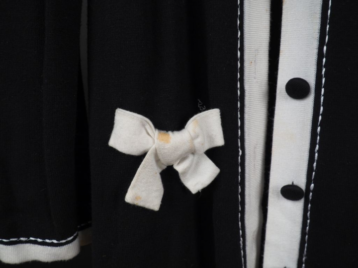 MISS PAPILLON Robe noire à décor de nœuds de ruban et d'un galon blanc