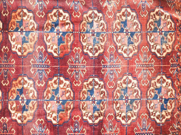 Tapis Boukhara fond lie de vin (usures). Dim. 228 x 154 cm