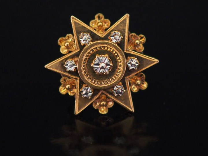 Broche en forme d'étoile en or jaune, à décor de fleurettes. 2,5 x 2,5