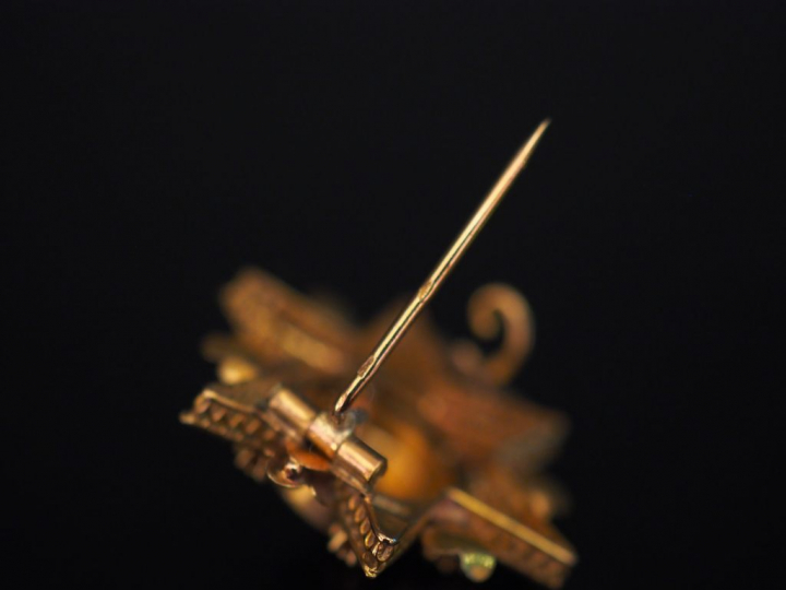 Broche en forme d'étoile en or jaune, à décor de fleurettes. 2,5 x 2,5