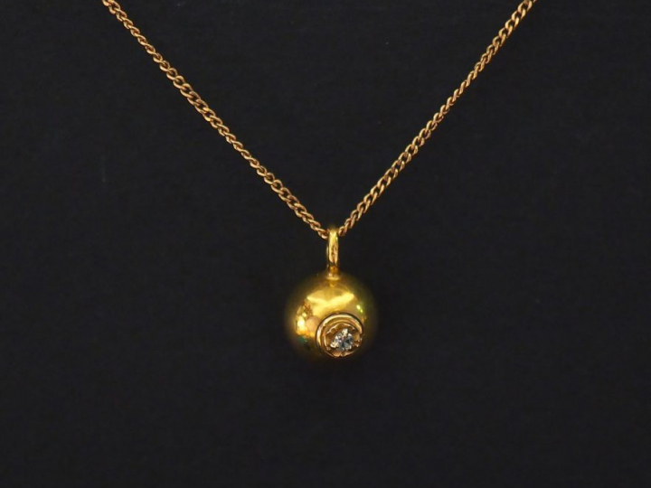 Pendentif en or jaune en forme de boule sertie d'un petit éclat de dia
