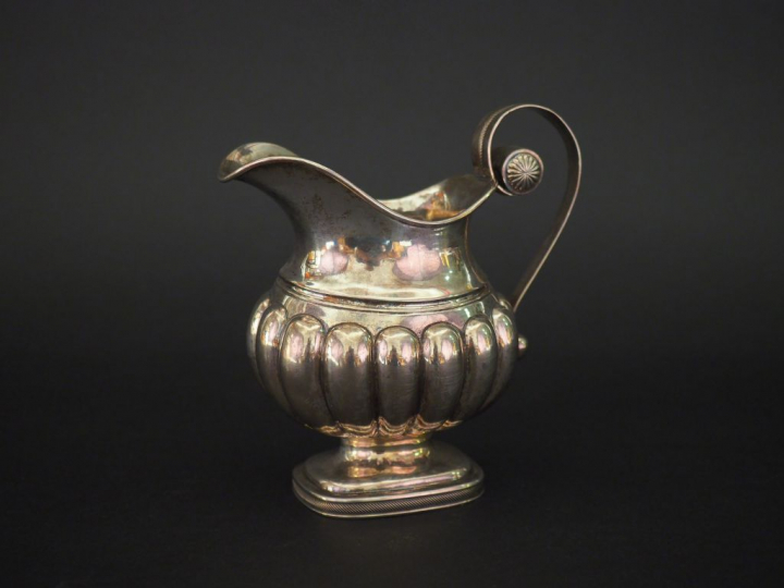 Pichet sur piédouche en argent, à décor de godrons.  Anse à enroulemen