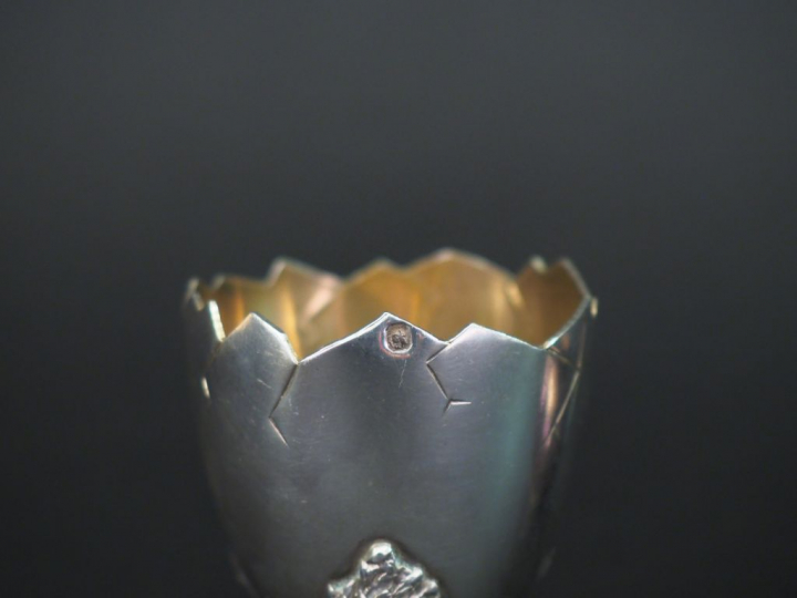 Coquetier en argent reposant sur un piètement tripode figurant des pat