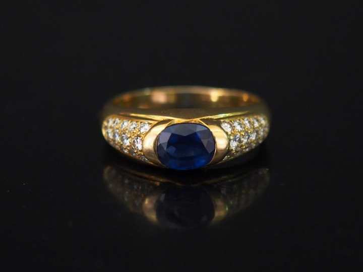 Bague jonc en or jaune, sertie en son centre d'une pierre bleue épaulé