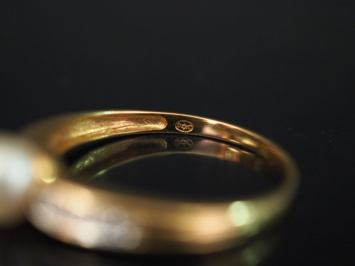 Bague en or jaune, sertie en son centre d'une perle blanche épaulée de