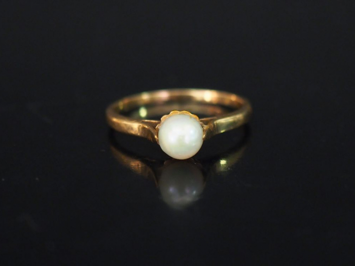 Bague en or jaune, sertie en son centre d'une perle blanche. TDD. 55 P