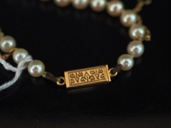 Collier de perles blanches disposées en chute.  Fermoir en or jaune, à