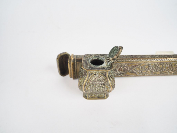 Encrier arabe en laiton ciselé à décor de calligraphie. L. 32 cm.