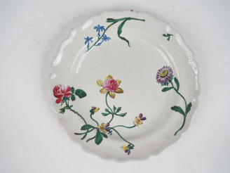 Vente aux enchères MARSEILLE.  Assiette en faïence de petit-feu à décor d’un jeté de fleu
