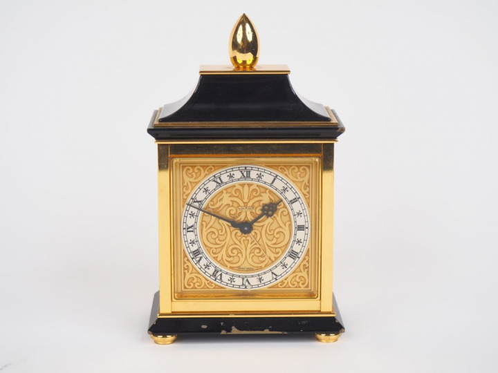 LUXOR. Pendulette de table en laiton, cadran à décor de rinceaux. Sign