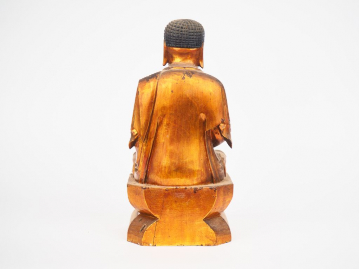 Statuette en bois laqué et doré représentant un boudha assis sur un do