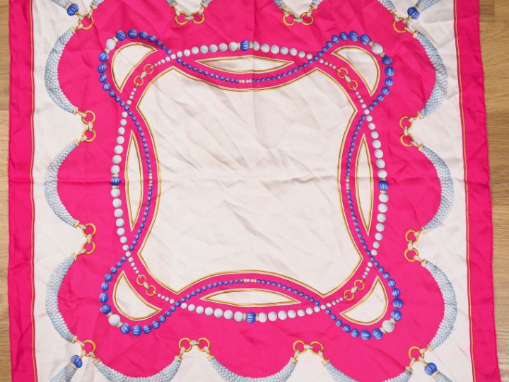 Must de CARTIER.  Foulard probablement en soie de couleur fushia, crèm