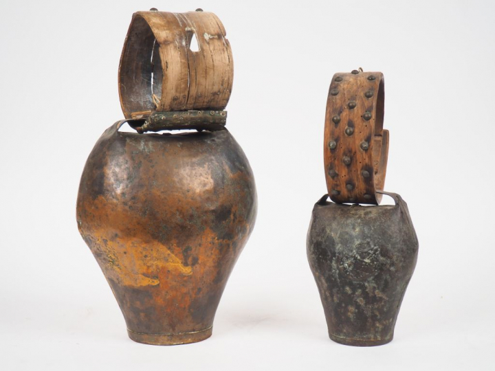 2 différentes sonailles en bois et métal. H. 40 et 33 cm.