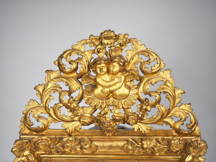 Glace XVIIIe en bois sculpté doré à décor de fleurs, fronton ajouré à 