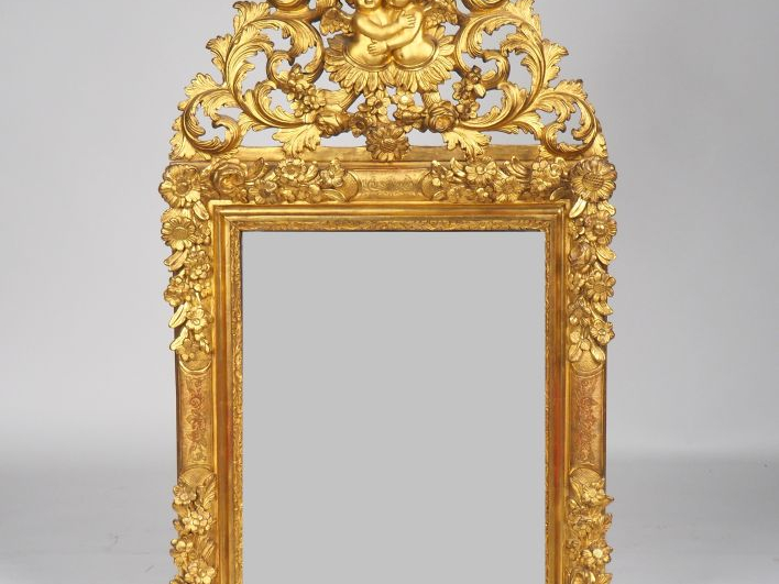 Glace XVIIIe en bois sculpté doré à décor de fleurs, fronton ajouré à 