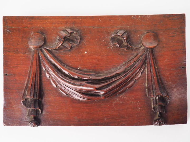 Plaque en acajou sculpté à décor de draperie. Dim. 11,8 x 19,5 cm.