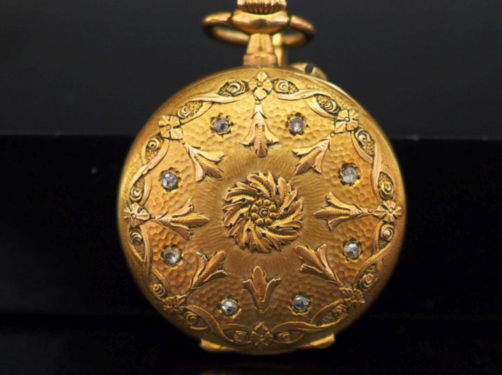 Montre de col en or jaune.  Cadran à chiffres arabes pour les heures. 