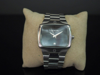 Vente aux enchères NIXON,  Montre bracelet en acier.  Cadran rectangulaire à fond noir ag