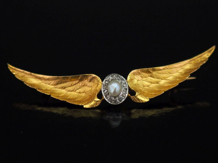 Broche 1900 en or jaune, à décor de deux ailes déployées entourant un 