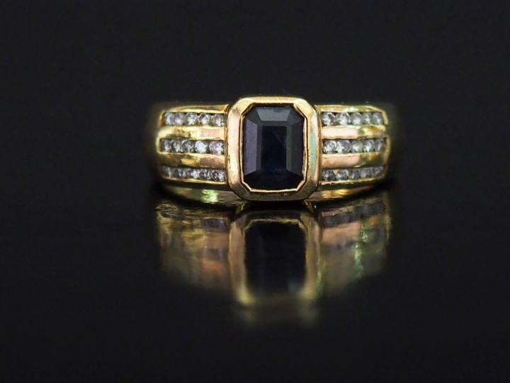 Bague moderne en or jaune, sertie en son centre d'une pierre bleue.  L