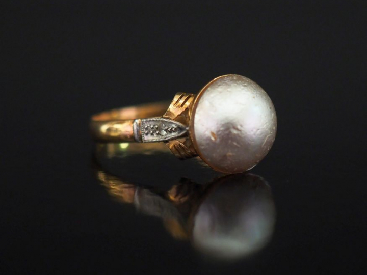 Bague en or jaune, sertie en son centre d'une demi-perle.  Jolie montu