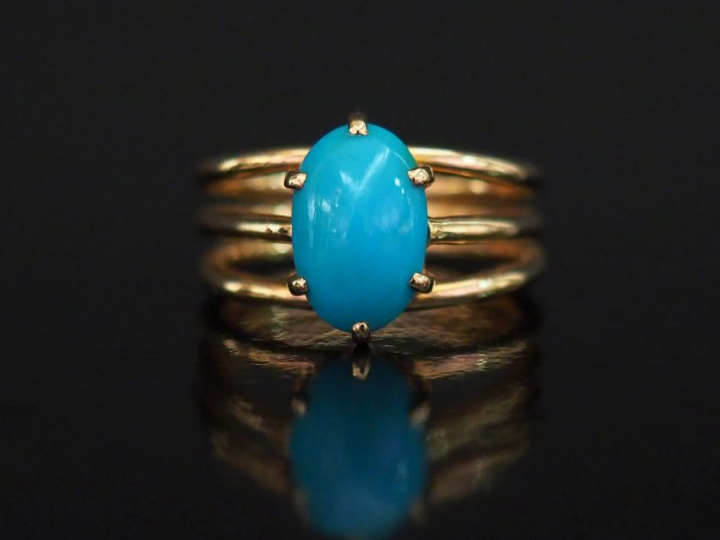 Bague en or jaune, sertie en son centre d'un turquoise (?) en cabochon