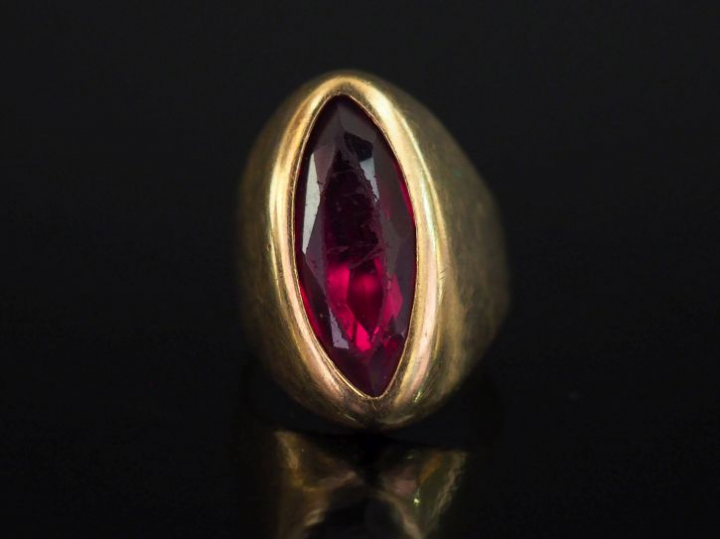 Bague en or jaune, sertie en son centre d'une pierre rouge de forme ma