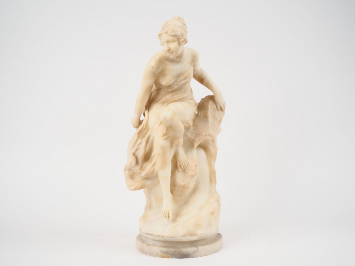 Sculpture en albatre "jeune fille dénudée sur un rocher". Signée (rest