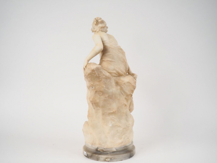 Sculpture en albatre "jeune fille dénudée sur un rocher". Signée (rest