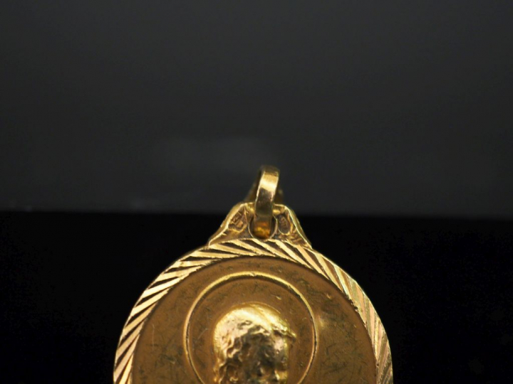 Médaille religieuse en or jaune, figurant une jeune sainte en prière l